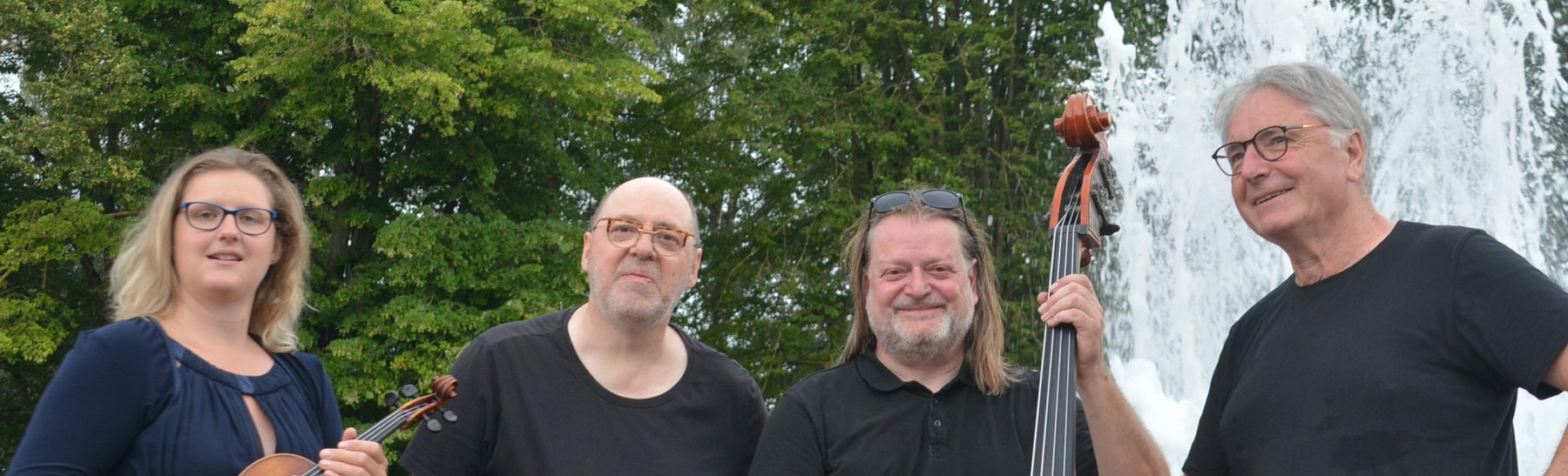 Die vier Musiker*innen von JazzExclusive mit Geige und Kontrabass vor einem Springbrunnen